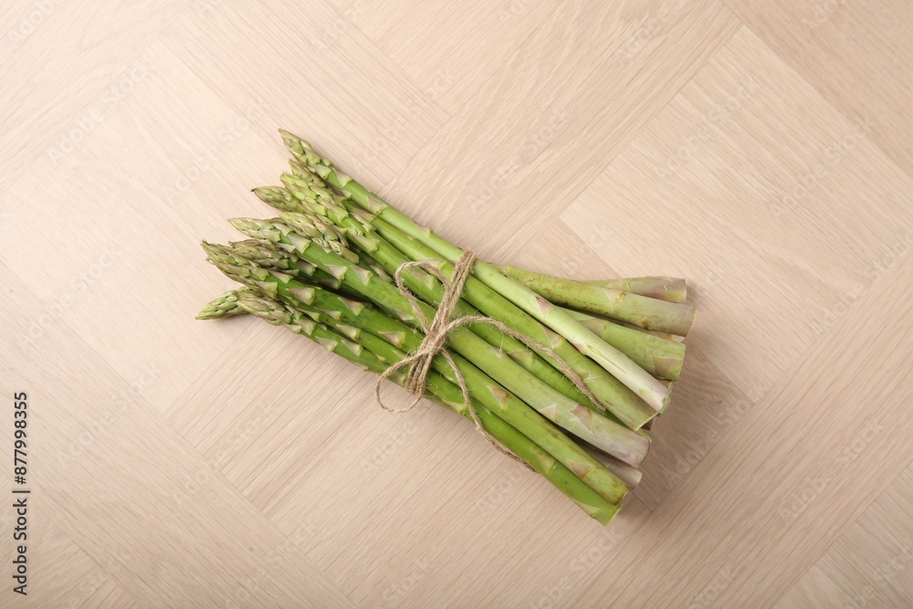 Bunch of fresh green asparagus stems on wooden table, top view Bunch of fresh green asparagus stems on wooden table, top view