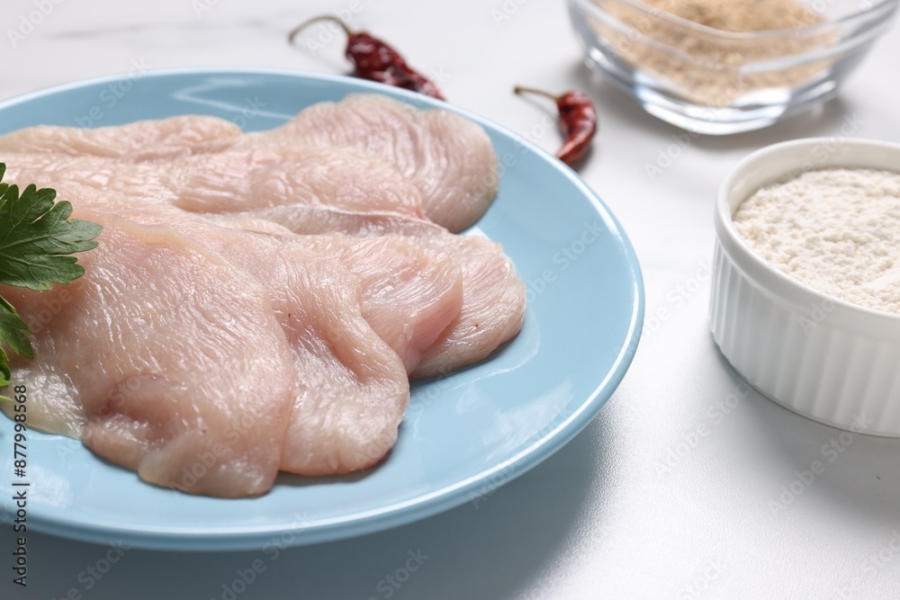 Cooking schnitzel. Raw meat, flour and chili peppers on white table, closeup Cooking schnitzel. Raw meat, flour and chili peppers on white table, closeup
