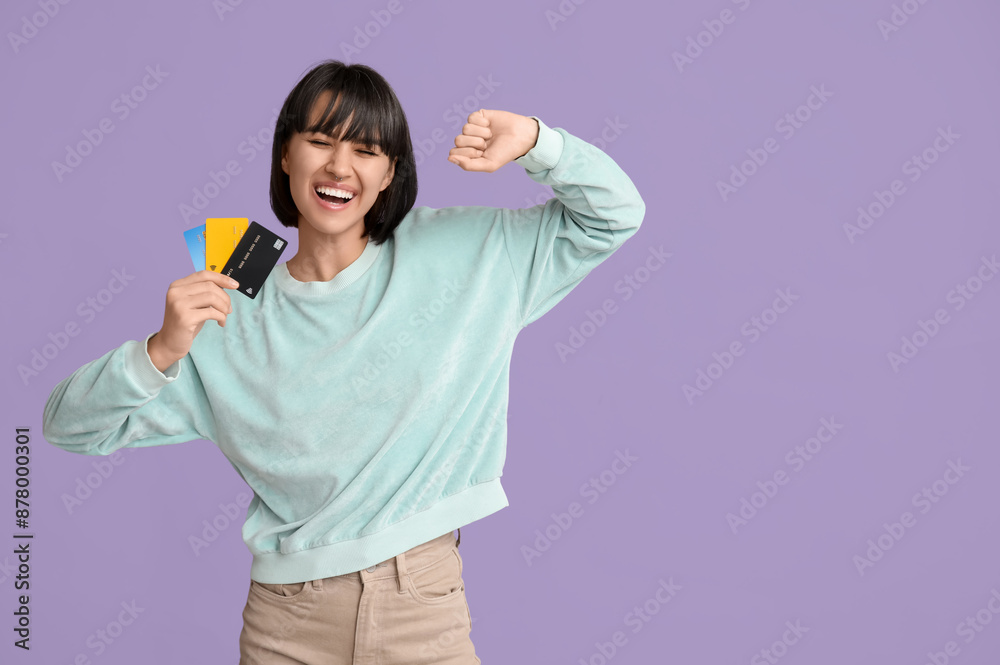 Happy young woman with credit cards on lilac background Happy young woman with credit cards on lilac background