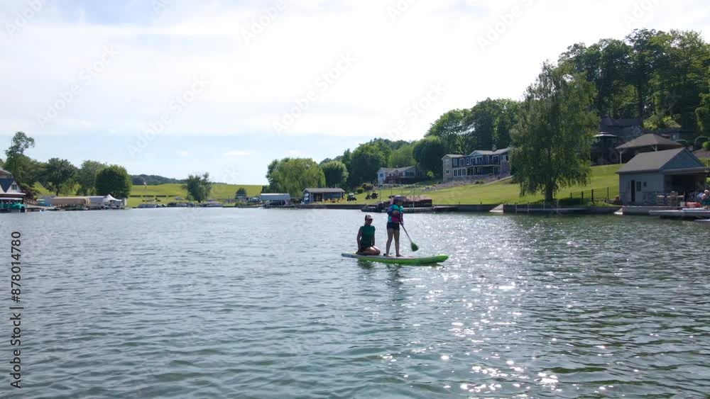 Woman and Child Ride Paddle Board Together on Lake Woman and Child Ride Paddle Board Together on Lake