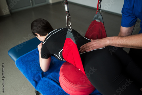 Red cord strap exercises to activate small muscles. Young girl is going through red cord rehabilitation to heal from injury. Red cord physiotherapy to recover from pain in muscles. photo