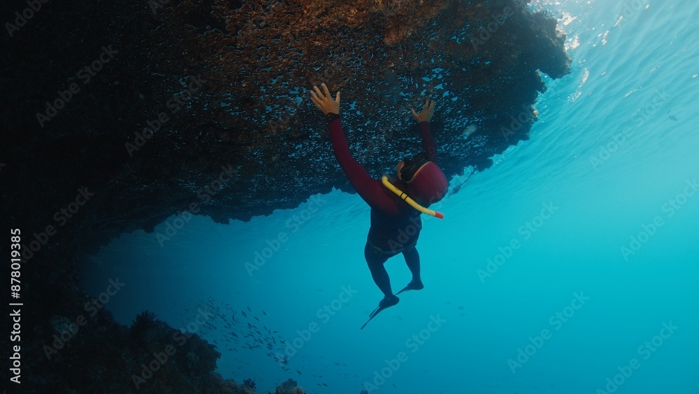 Naklejka premium Man freedives underwater in the tropical sea in Raja Ampat in Indonesia