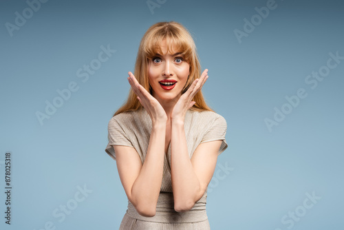 Surprised woman with open mouth posing on blue background