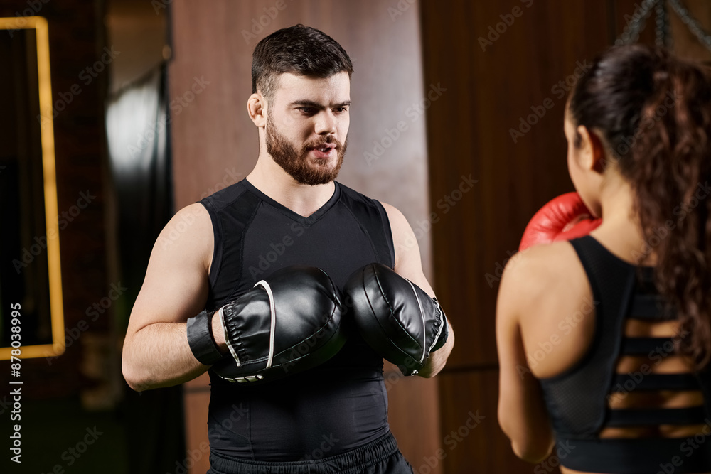A male trainer and a brunette sportswoman boxing in a gym, showcasing strength and teamwork. A male trainer and a brunette sportswoman boxing in a gym, showcasing strength and teamwork.