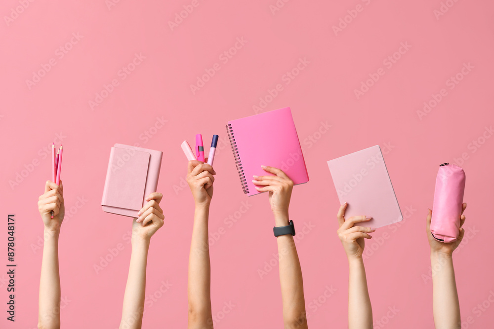 Many hands with notebooks, stationery and pencil case on pink background Many hands with notebooks, stationery and pencil case on pink background