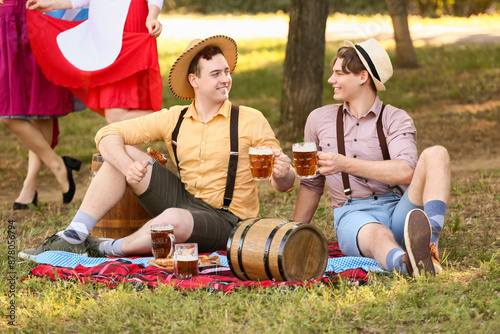 Young men in traditional German clothes with beer outdoors. Octoberfest celeb...