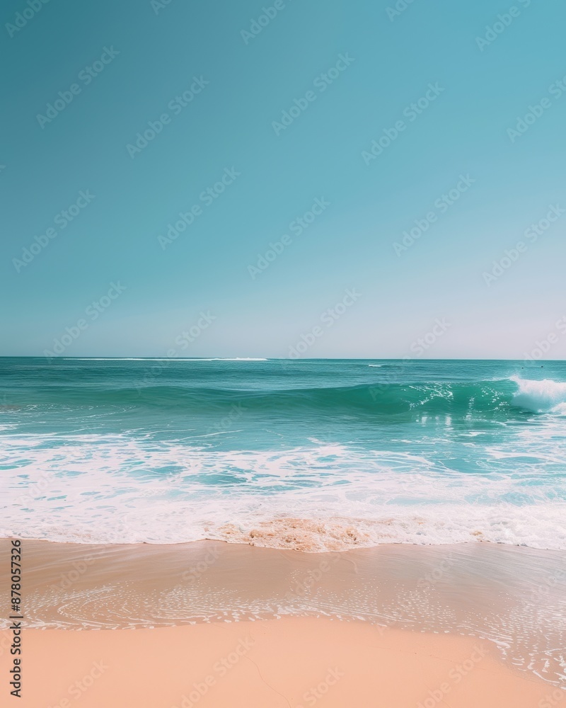 Obraz premium Serene beach scene with clear turquoise water, gentle waves, and sandy shore under a bright blue sky