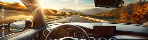 A focused driver is behind the wheel, with a view of the road and a beautiful landscape ahead, as seen through the windshield of the car on a sunny day.
