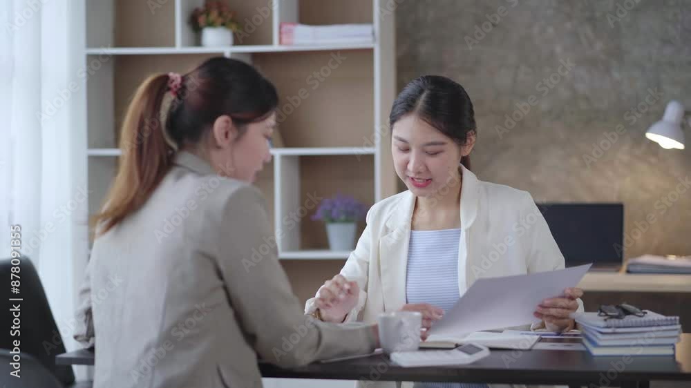 Two businesswomen engage in a professional discussion, reviewing documents in a modern office. Collaboration and productivity are highlighted in this interaction Two businesswomen engage in a professional discussion, reviewing documents in a modern office. Collaboration and productivity are highlighted in this interaction