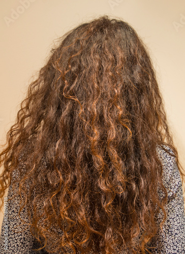 Women's long, curly, dry, and frizzy hair is damaged by dyeing and perming. photo