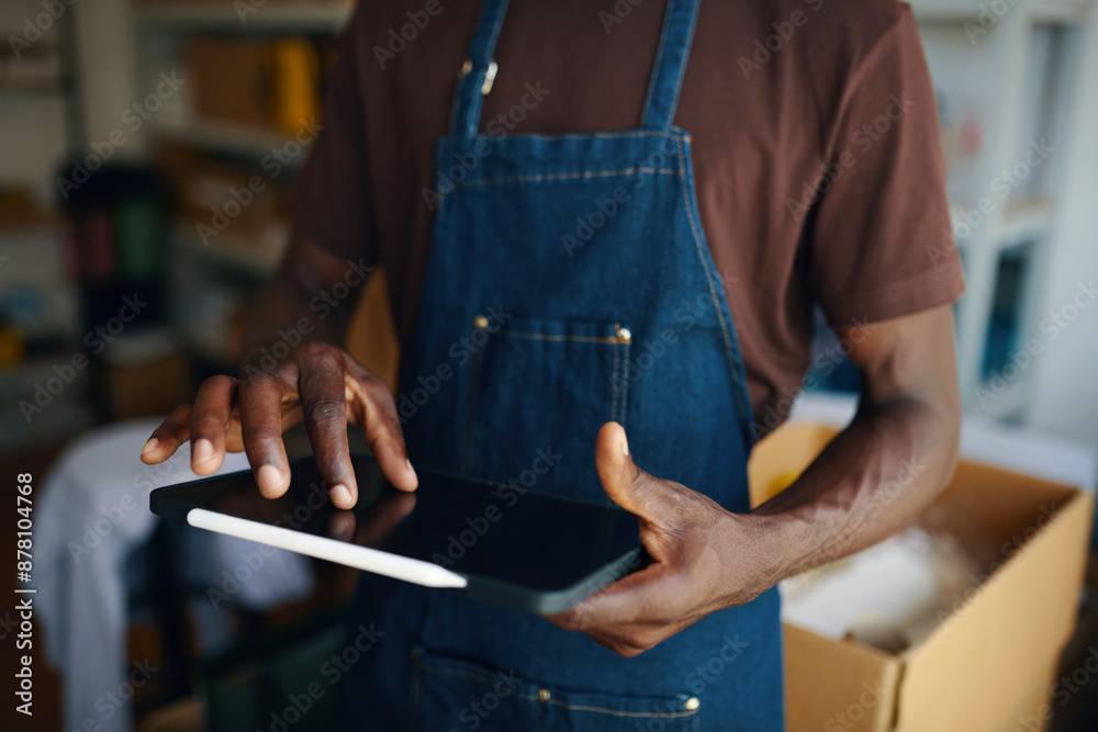 Obraz premium Close-up of worker checking online orders on tablet pc while working in warehouse