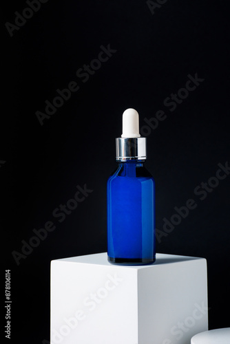 Blue glass cosmetic bottle, Skin care or sunscreen cosmetic with stylish props on black background.