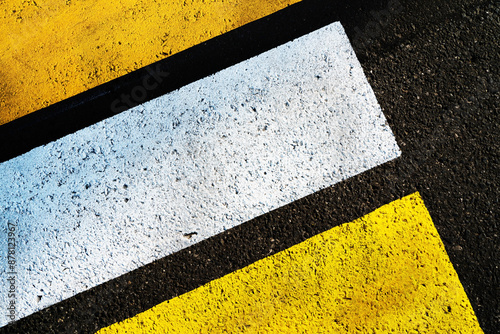 Close up of a white rectangle and yellow lines painted on a black asphalt road