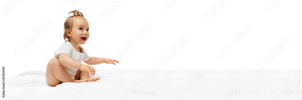 Happy little baby girl, child in bodysuit siting on bed and playing, smiling isolated on white background. Concept of childhood, care, healthy, infancy, life, motherhood. Banner. Copy space for ad