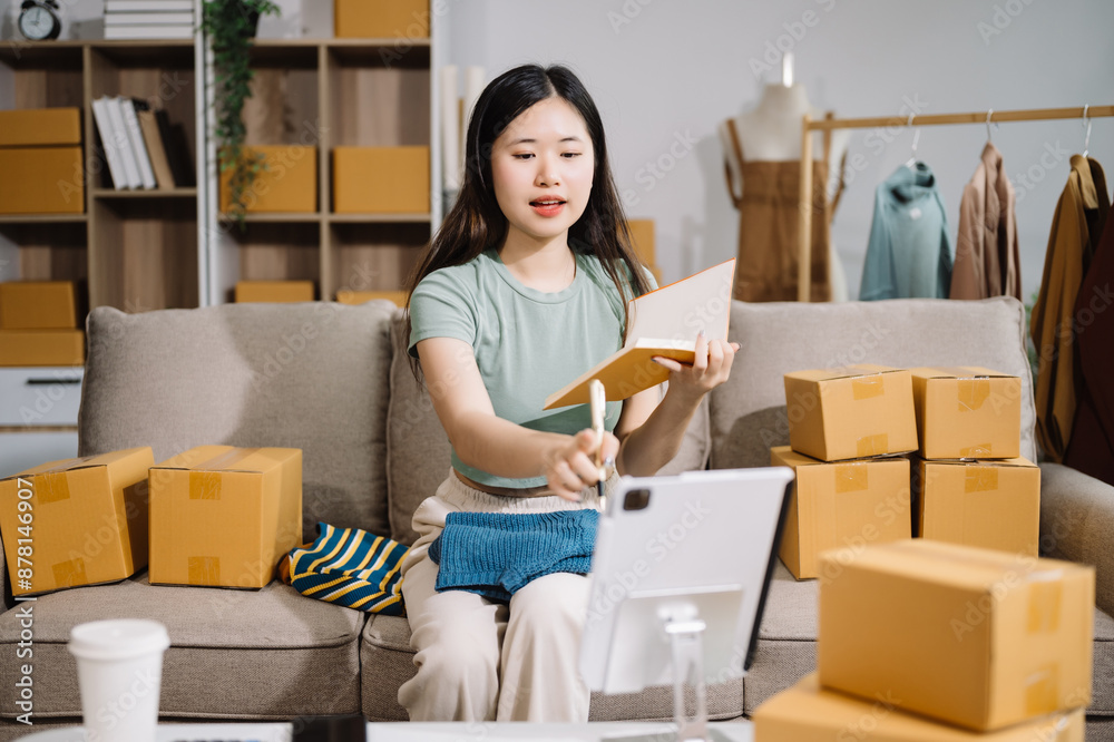Startup small business SME, Entrepreneur owner woman using smartphone or tablet taking receive and checking online purchase shopping order Startup small business SME, Entrepreneur owner woman using smartphone or tablet taking receive and checking online purchase shopping order