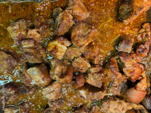 Pieces of fried meat in a mixture of red spices close-up, top view. Flat lay.