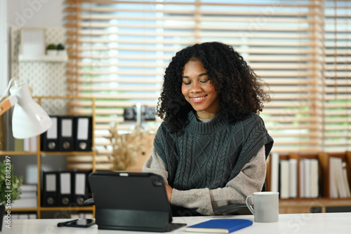 Portrait of African American woman freelancer working with digital tablet in comfortable workplace