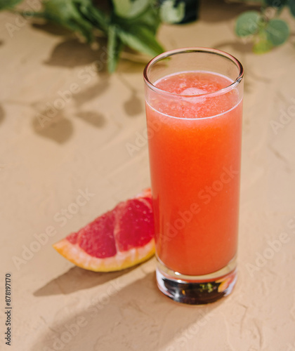 Fresh grapefruit juice glass on sandy surface