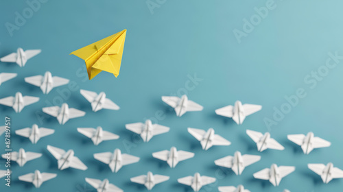 A yellow paper plane stands out while leading a group of white paper planes, symbolizing leadership, innovation, and uniqueness.