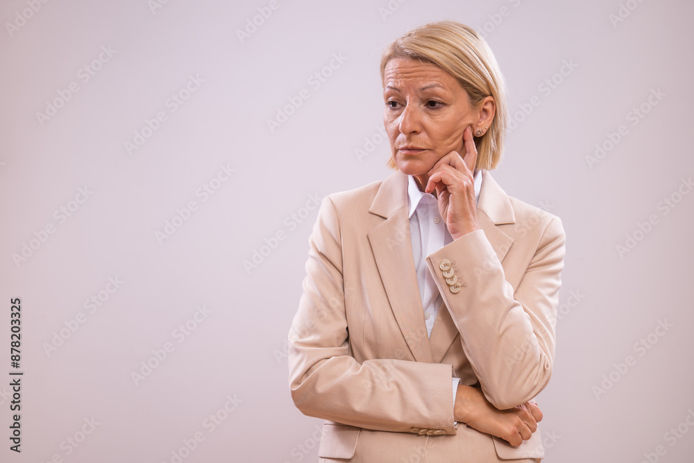 Portrait of depressed and tired mature businesswoman thinking on gray background. Portrait of depressed and tired mature businesswoman thinking on gray background.