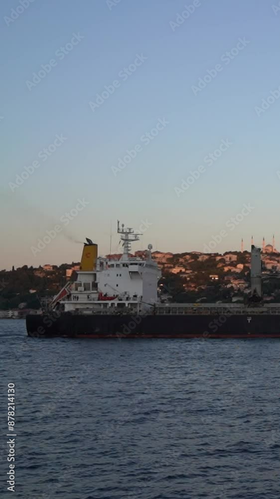 Dramatic view of a cargo ship sailing through the Bosphorus Strait at dusk Dramatic view of a cargo ship sailing through the Bosphorus Strait at dusk