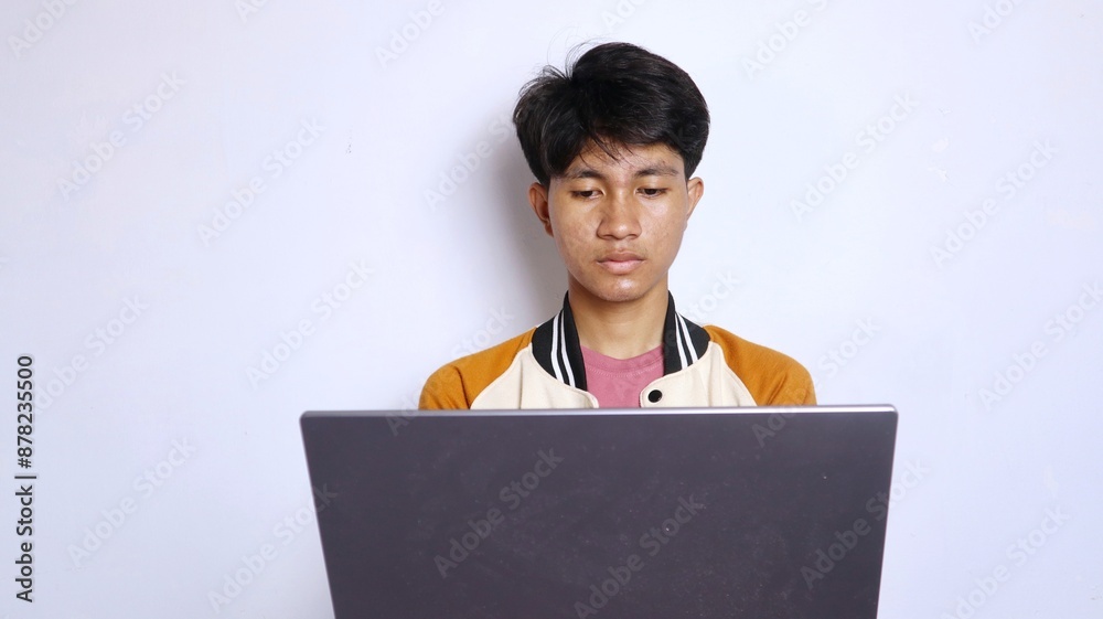 casual shocked college young handsome asian man wearing study jacket in front of laptop isolated white background. online lectures, exams, studying casual shocked college young handsome asian man wearing study jacket in front of laptop isolated white background. online lectures, exams, studying