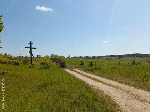 green field, road and wooden cross