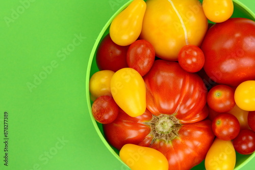 Different Kinds of Organic Tomatoes in a Bowl isolated on green background