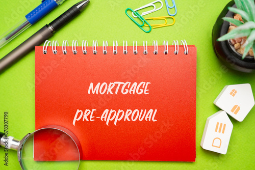 Mortgage pre-approval concept. Preliminary evaluation by a lender to determine the maximum loan amount a borrower can qualify for based on their financial status. Notepad, houses and magnifying glass