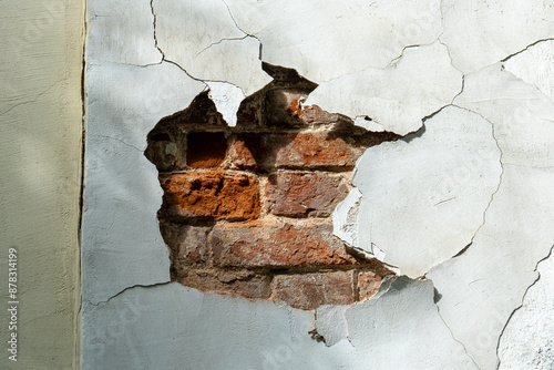 Old rough background. Old house wall with cracked and falling off plaster and exposed brickwork