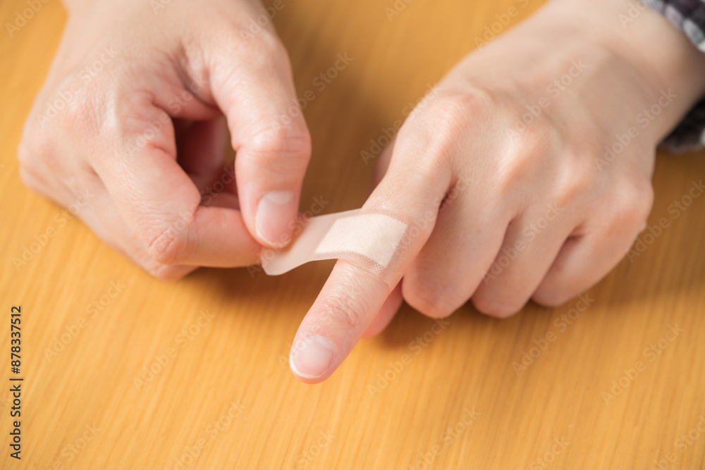 指に絆創膏を貼る人の手元 指に絆創膏を貼る人の手元