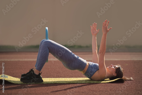 Lying on a mat, the woman engages in a bridge pose using a fitness ring, focusing on her glutes and core. benefits of incorporating strength training into regular workouts for a balanced physique. photo