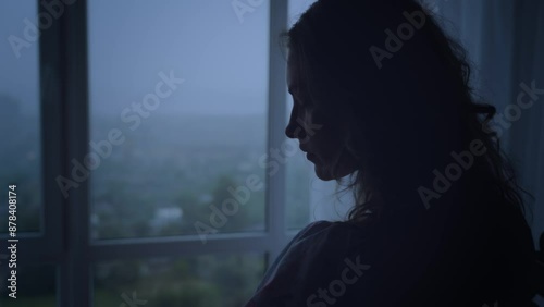 black dark silhouette of young woman crying looking at window rain drops falling rainy weather mood depression sadness loneliness emotion back view. Adult Girl sad tear-stained face. video footage 4k