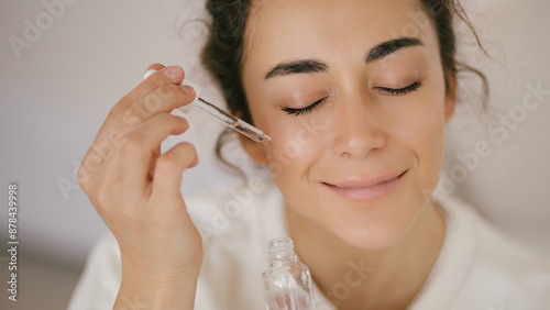 Young woman 30 years old applying face oil on her skin.