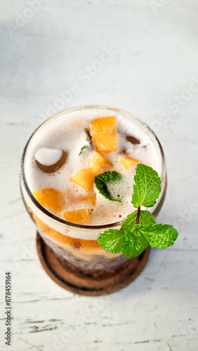 Mango iced tea with mint leaves which tastes very refreshing. Iced tea on a white table is very fresh to enjoy in the hot summer