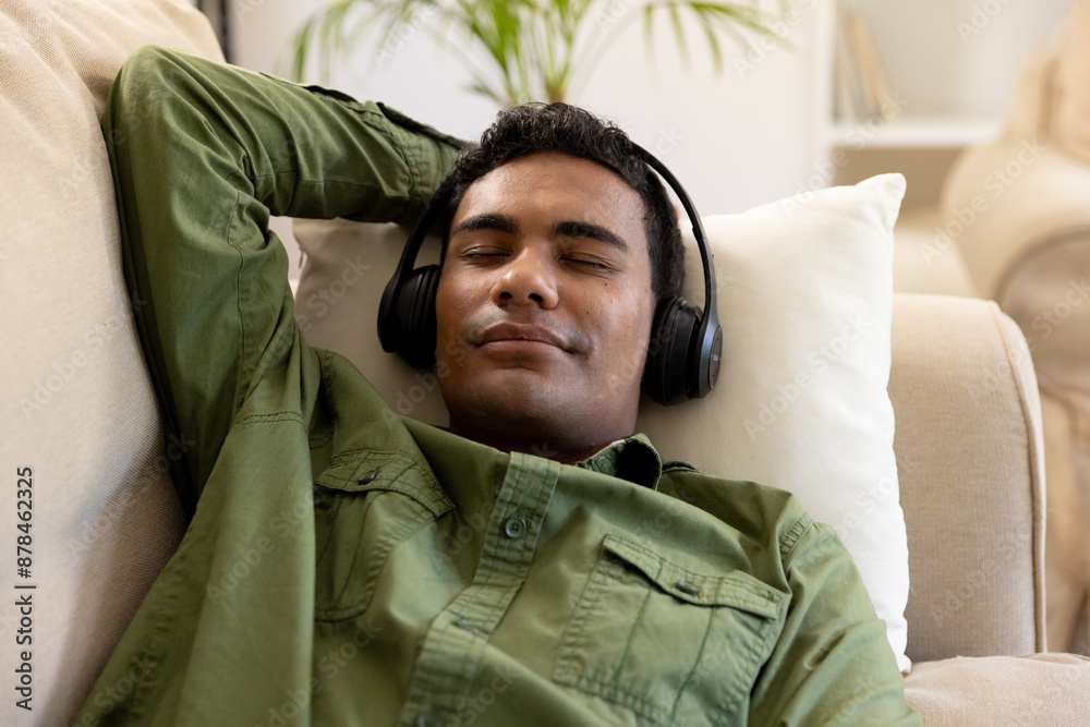 Obraz premium Young biracial man relaxes at home with headphones