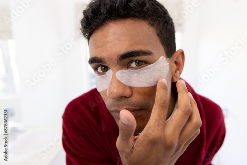 Schilderij op canvas Young biracial man applies skincare products at home