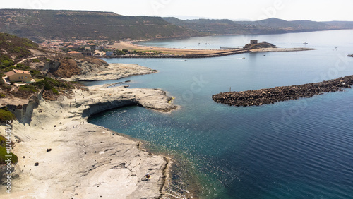A stunning aerial view of Cane Malu beach in Sardinia with the picturesque tourist town of Bosa Marina in the background. Volcanic rock formations and turquoise waters