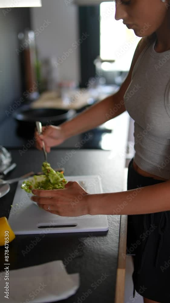 A woman is actively engaged in preparing a fresh salad in a welllit, contemporary kitchen A woman is actively engaged in preparing a fresh salad in a welllit, contemporary kitchen