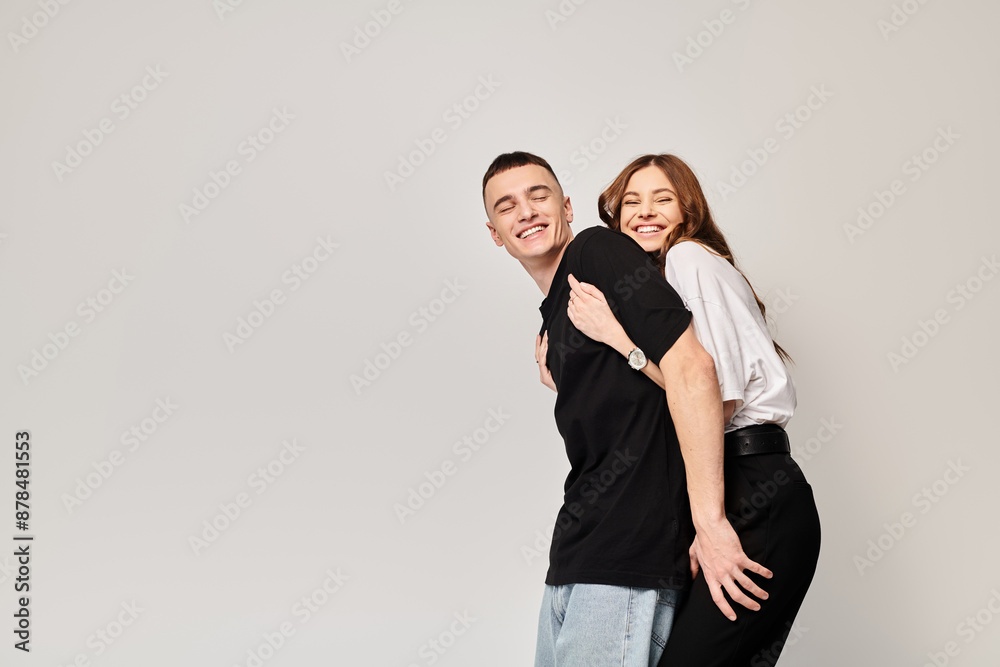 A man and woman, young couple, hugging each other affectionately in a studio with a grey background. A man and woman, young couple, hugging each other affectionately in a studio with a grey background.