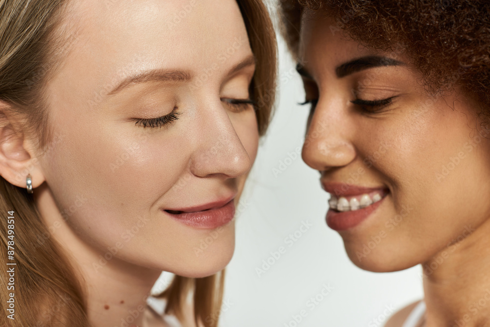 Two women, close together with eyes closed and lips parted, share a tender moment against a grey backdrop Two women, close together with eyes closed and lips parted, share a tender moment against a grey backdrop