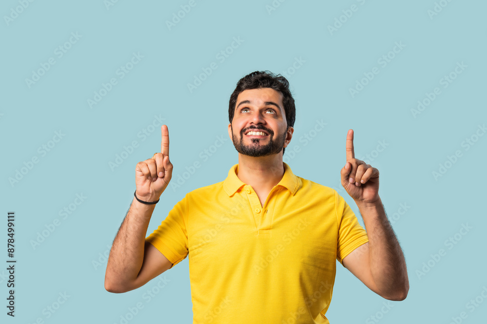 Fototapeta premium Happy Indian Asian Bearded Man Pointing at Copy Space, Looking Shocked, Blue Background