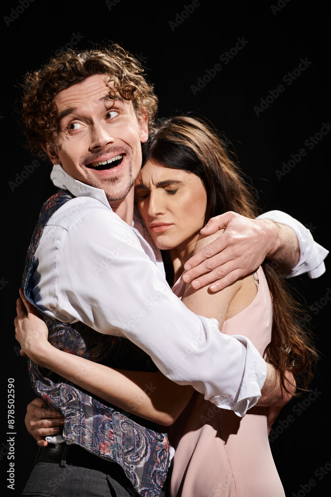 Obraz premium A handsome man and a beautiful woman embracing passionately during a theater rehearsal.