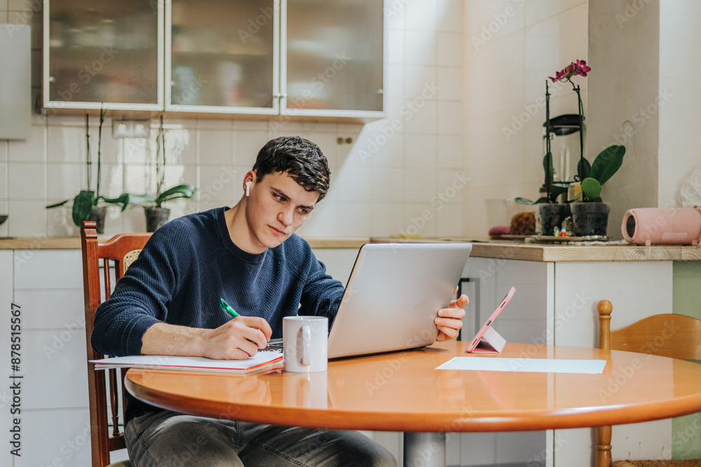 Young man studying at home with laptop and notebook Young man studying at home with laptop and notebook