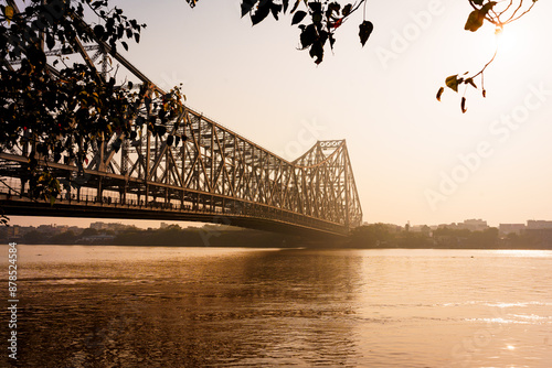 The Hooghly river and the iconic Howrah bridge in Calcutta are seen in the morning at sunrise. Example of indian architecture in Kolkata photo