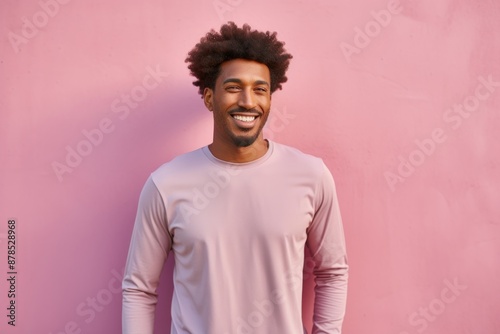 Portrait of a glad afro-american man in his 30s showing off a lightweight base layer isolated on pastel or soft colors background