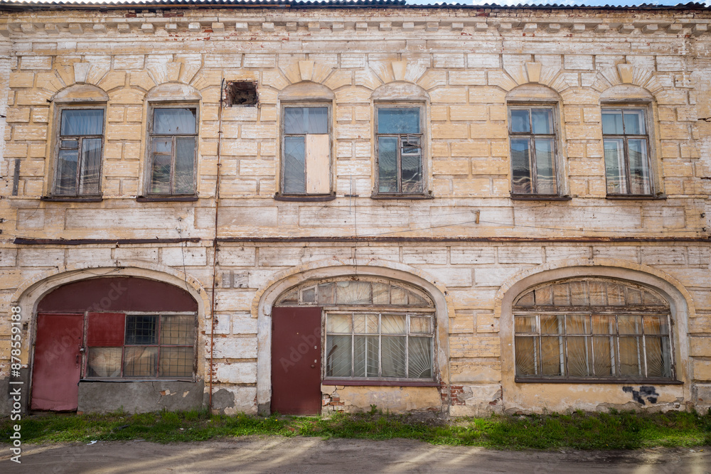 the facade of an old two-storey leaning brick building with large windows on the ground floor the facade of an old two-storey leaning brick building with large windows on the ground floor