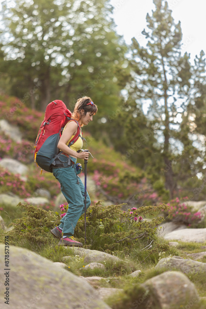 A woman is hiking up a hill with a backpack on her back. She is wearing a yellow shirt and blue pants. Concept of adventure and determination as the woman navigates the rocky terrain A woman is hiking up a hill with a backpack on her back. She is wearing a yellow shirt and blue pants. Concept of adventure and determination as the woman navigates the rocky terrain