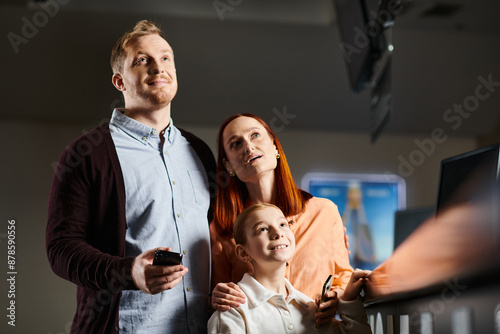 family standing side by side, radiating smiles and joy in a cinema setting.