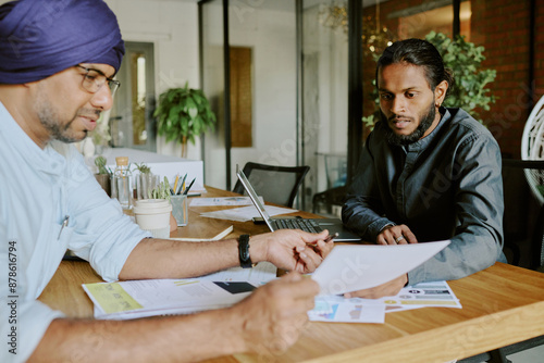 Experienced boss discussing last financial report with his best employee while sitting at wooden table © AnnaStills